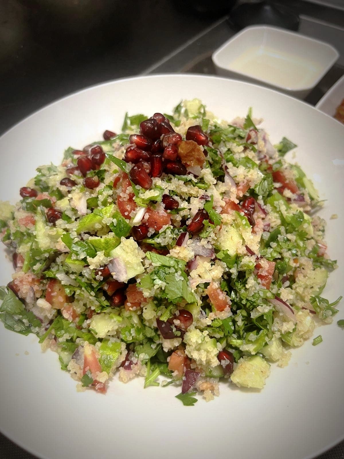 Fresh tabbouleh salad with bulgur, parsley, tomatoes, cucumbers, and glistening pomegranate seeds.